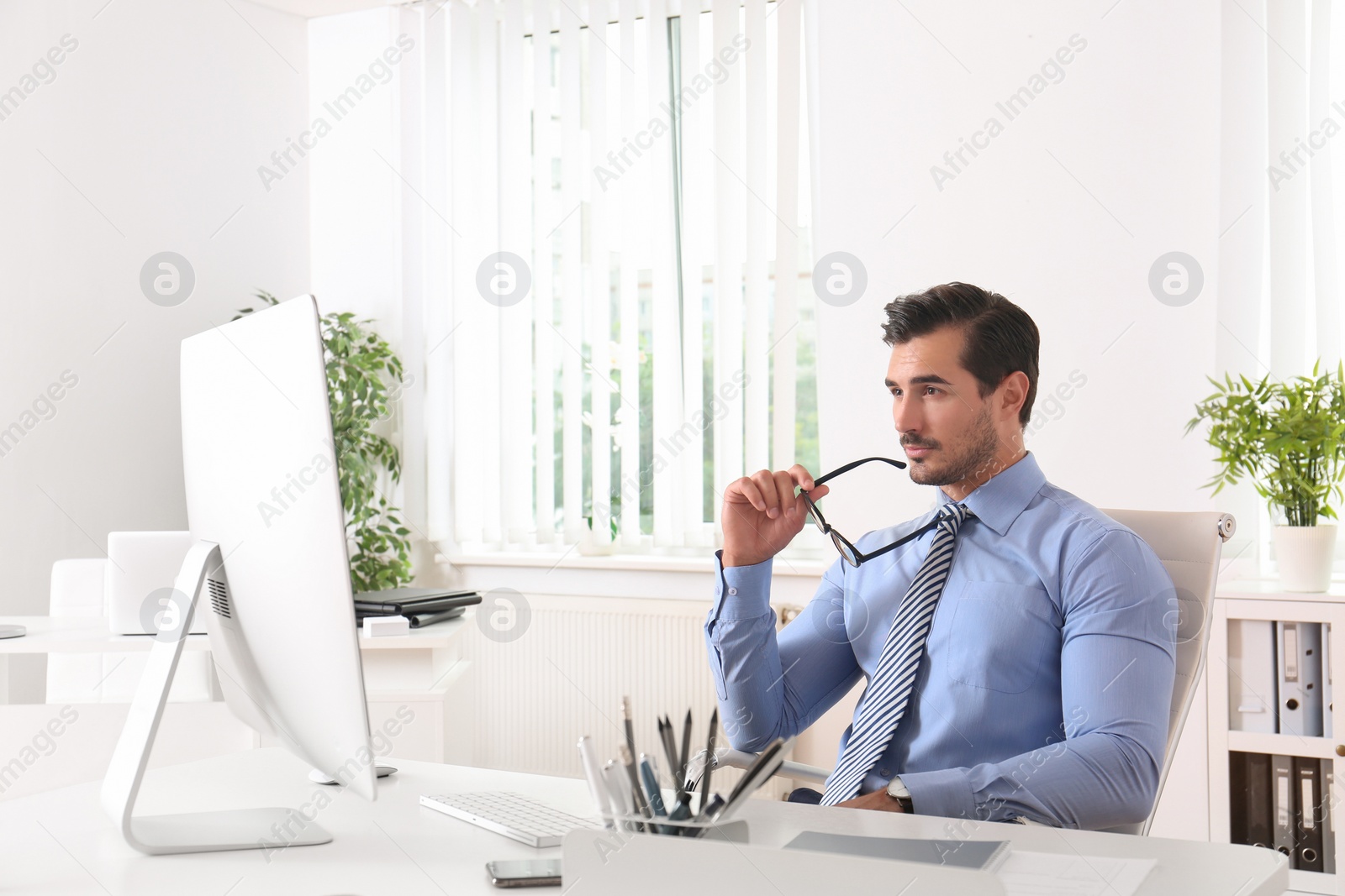 Photo of Handsome young man working with computer at table in office