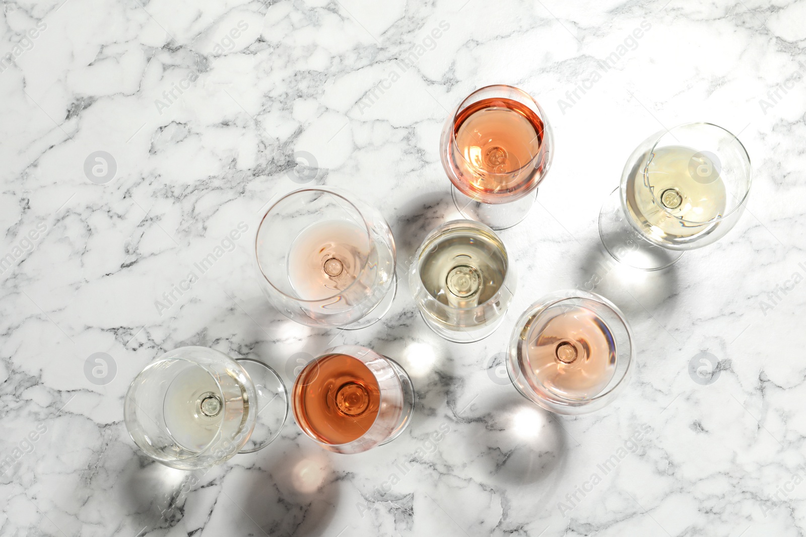 Photo of Different glasses with wine on marble background, flat lay