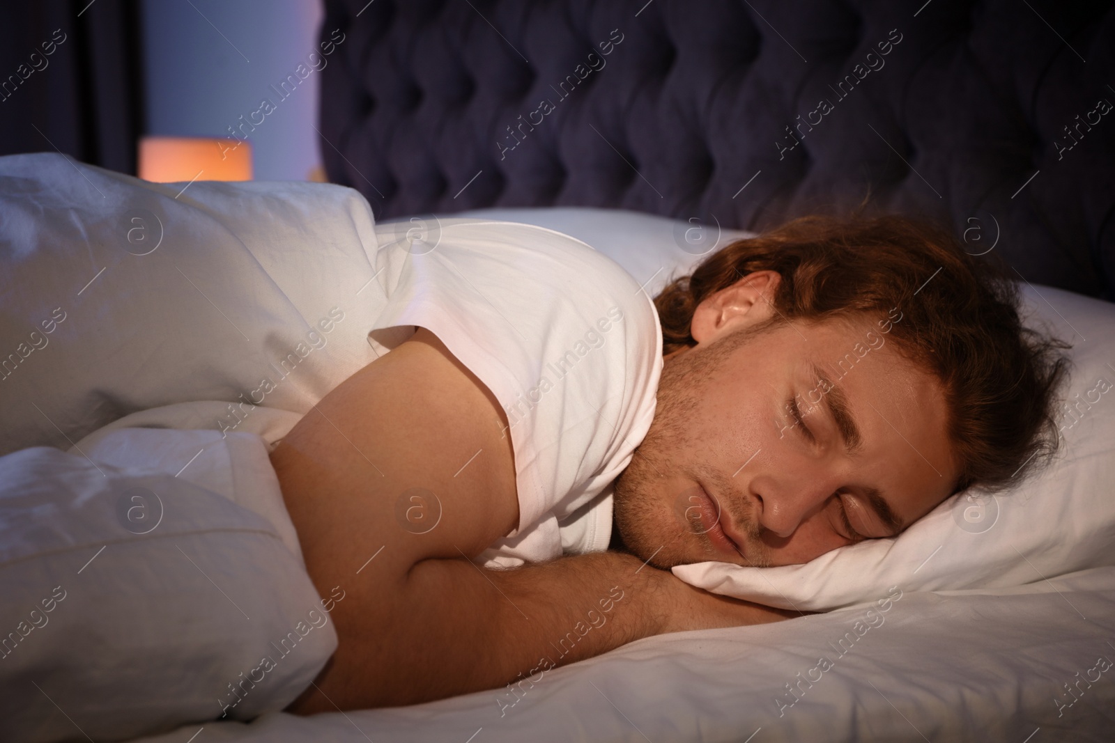 Photo of Handsome young man sleeping on pillow at night. Bedtime