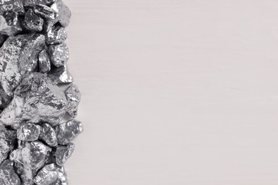 Photo of Pile of silver nuggets on white wooden table, flat lay. Space for text