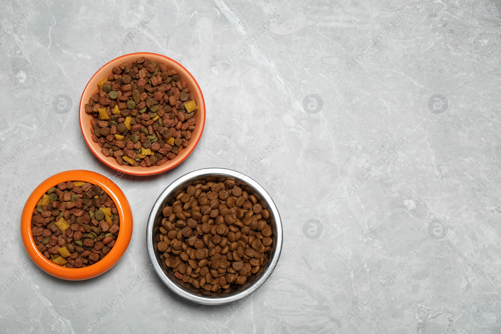 Photo of Pet bowls with dry food on light grey background, flat lay. Space for text