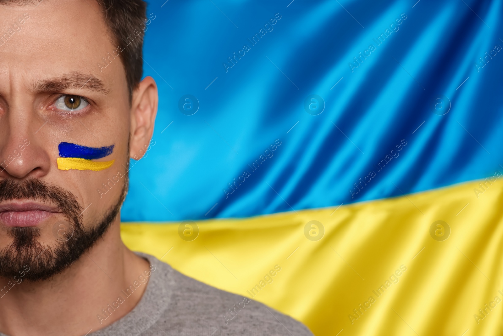 Photo of Man with face paint near Ukrainian flag, closeup. Space for text