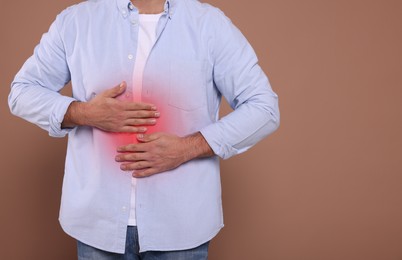 Image of Man suffering from stomach pain on brown background, closeup. Space for text