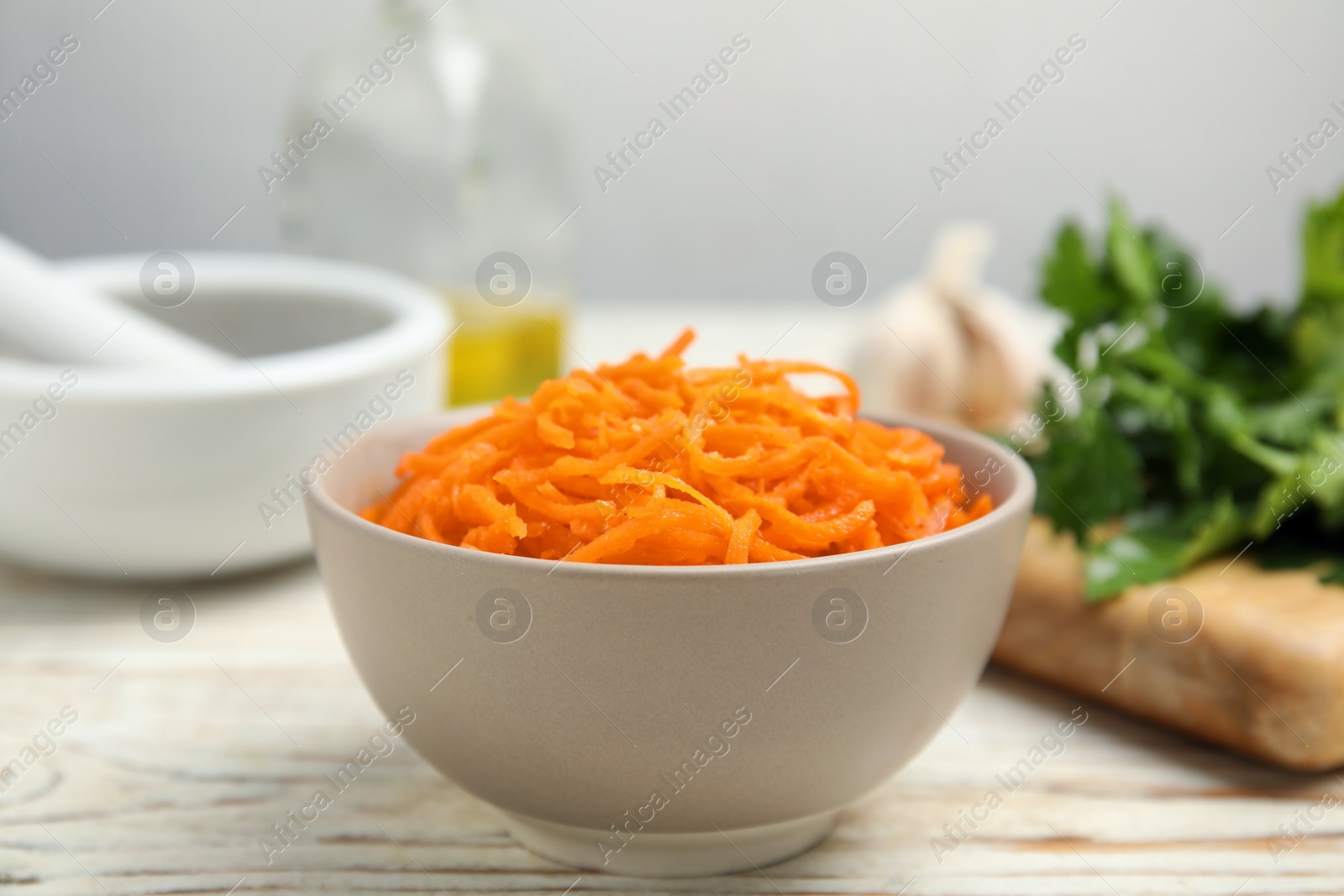 Photo of Delicious Korean carrot salad in bowl on white wooden table