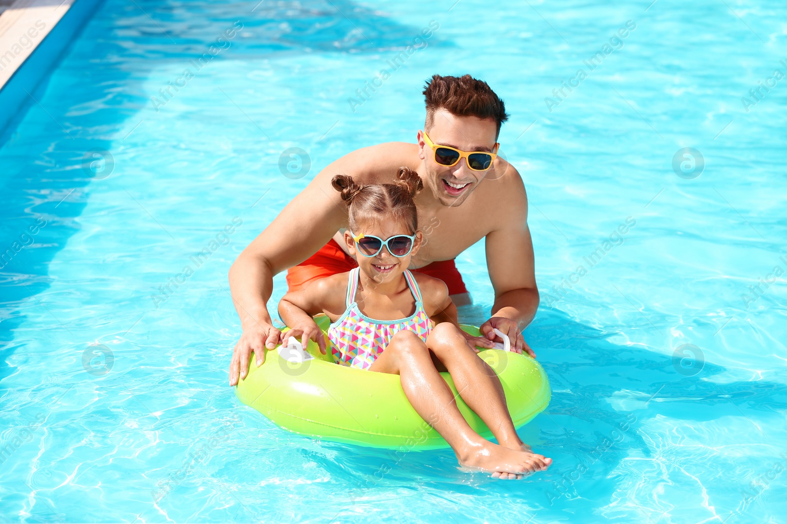 Photo of Happy father and little daughter with inflatable ring in swimming pool