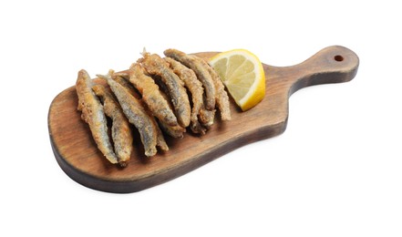 Wooden board with delicious fried anchovies and lemon on white background