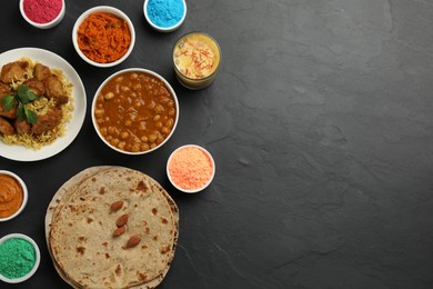 Photo of Traditional Indian food and color powders on black table, flat lay with space for text. Holi festival celebration