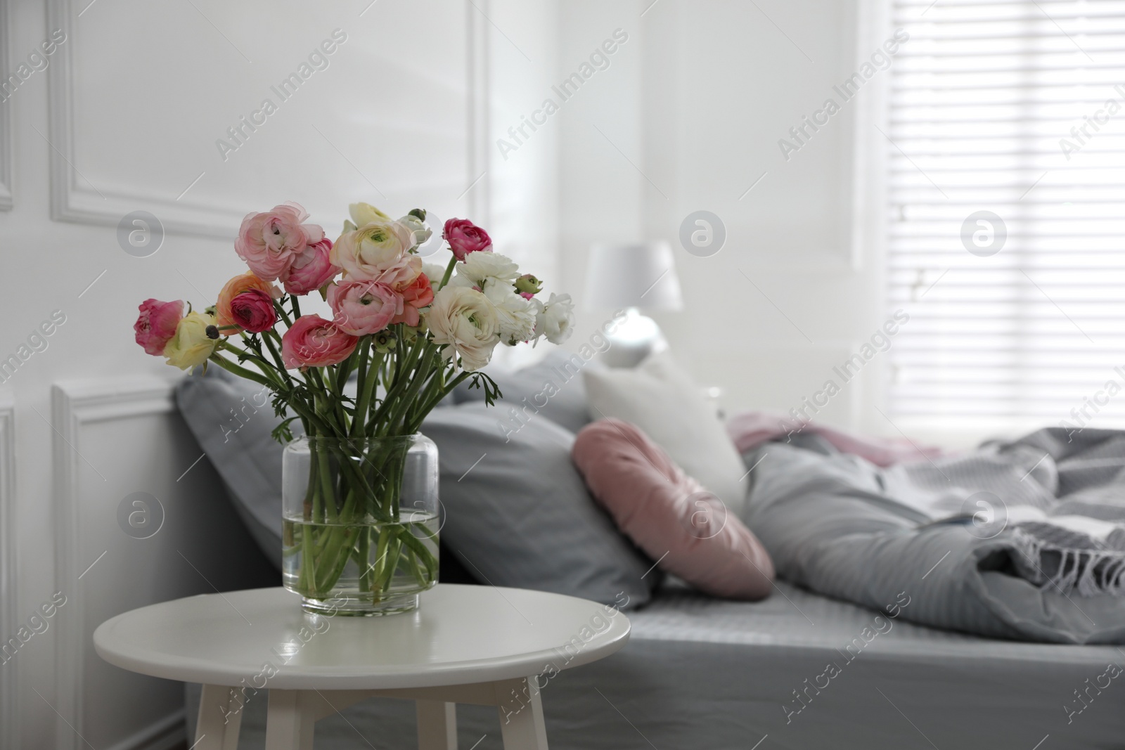 Photo of Bouquet of beautiful ranunculuses on table in bedroom. Space for text