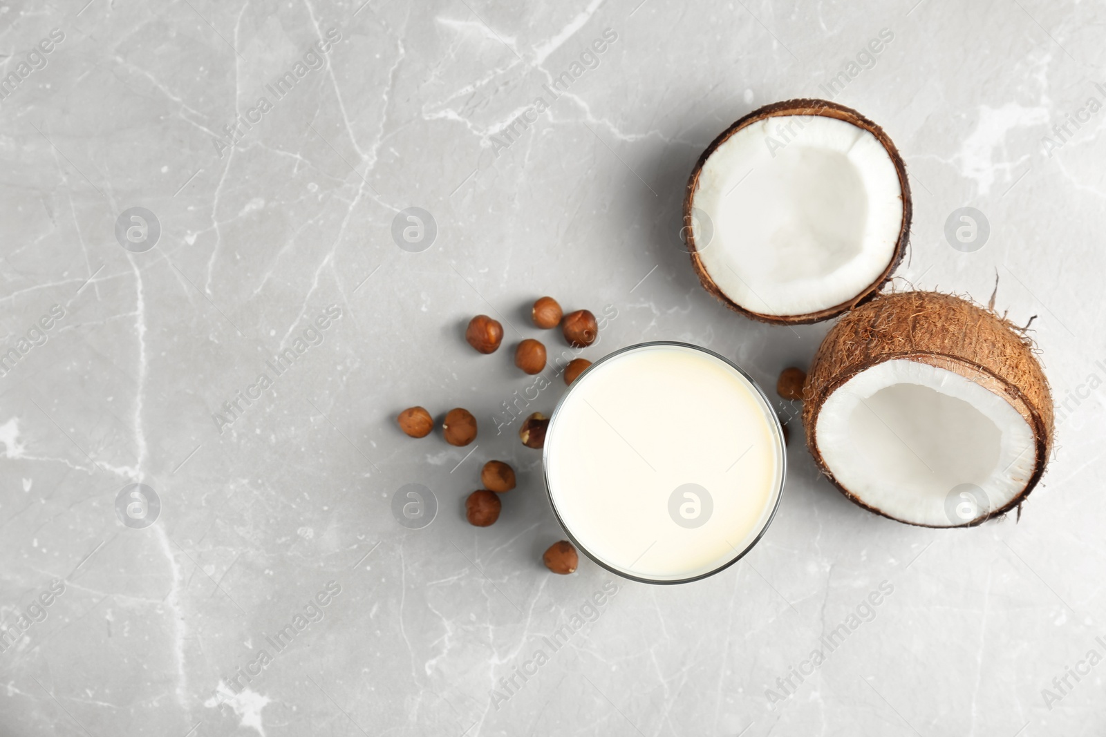 Photo of Glass with milk substitute and nuts on light background, top view