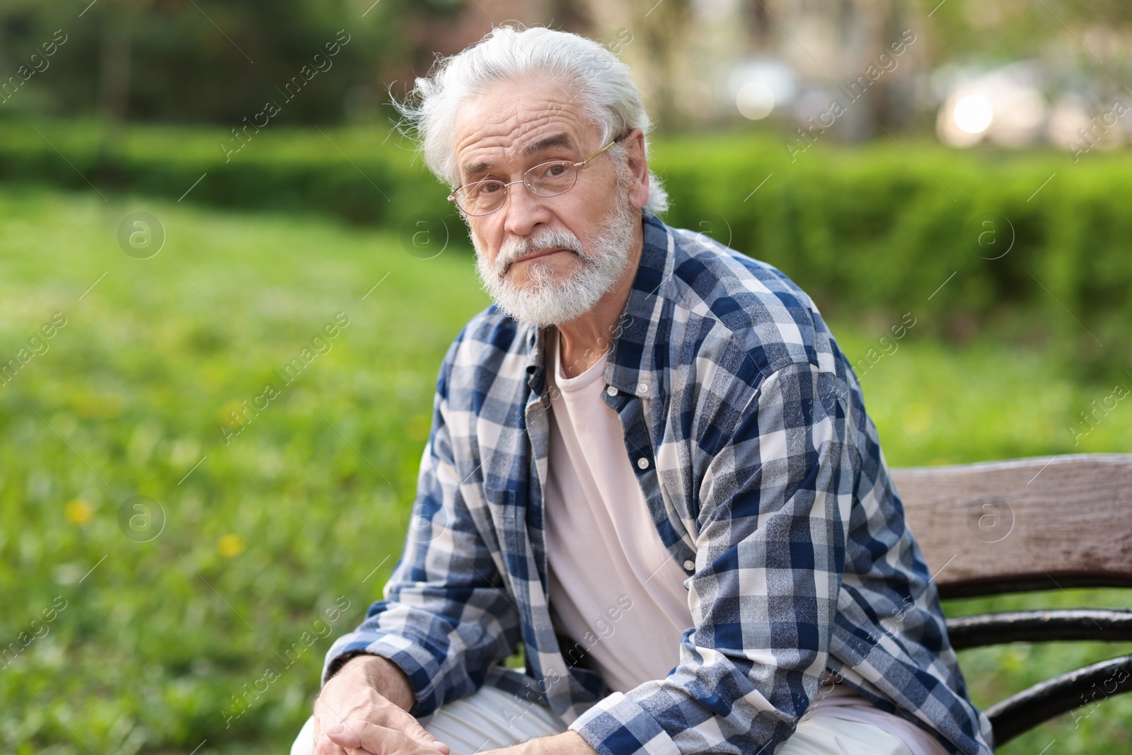 Photo of Portrait of happy grandpa with glasses on bench in park