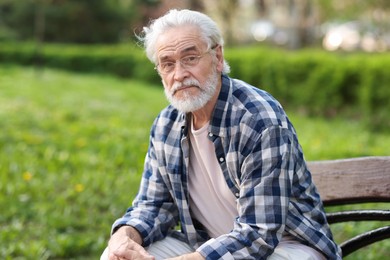 Photo of Portrait of happy grandpa with glasses on bench in park