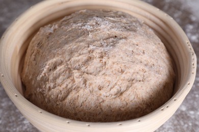 Photo of Fresh sourdough in proofing basket on table, closeup