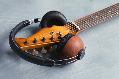 Photo of Modern electric guitar with headphones on color background, closeup view