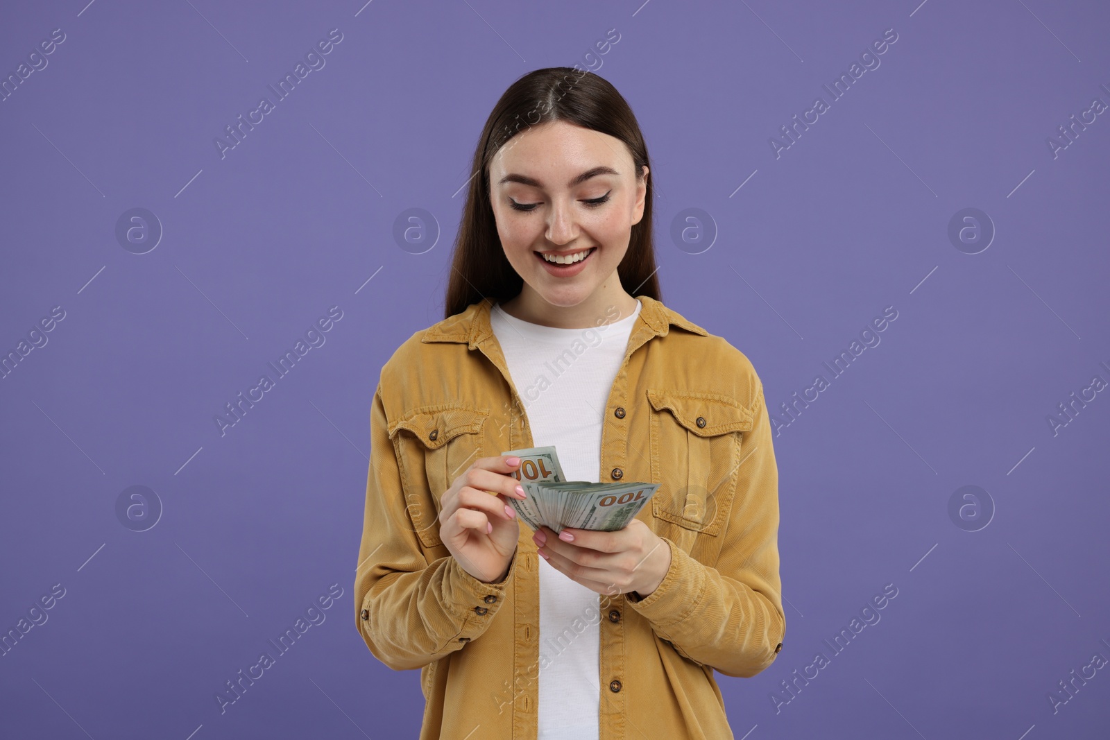 Photo of Happy woman with dollar banknotes on purple background