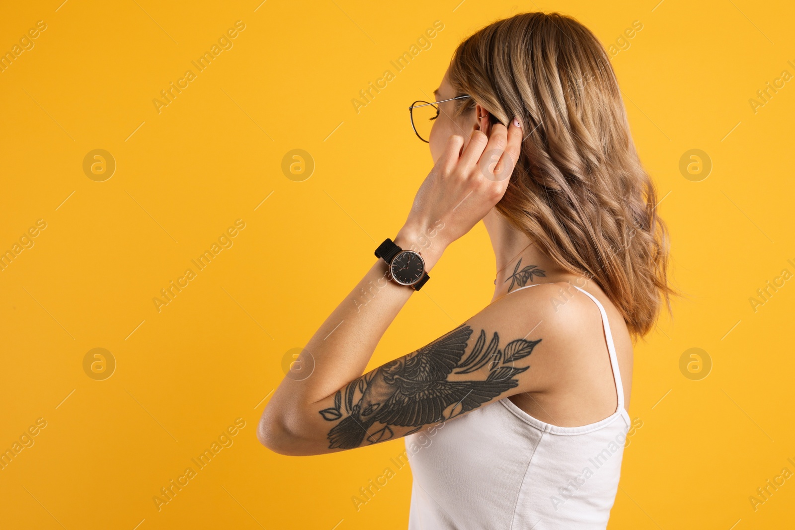 Photo of Beautiful woman with tattoos on body against yellow background. Space for text