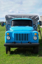 Photo of Light blue old truck on green lawn with fresh grass