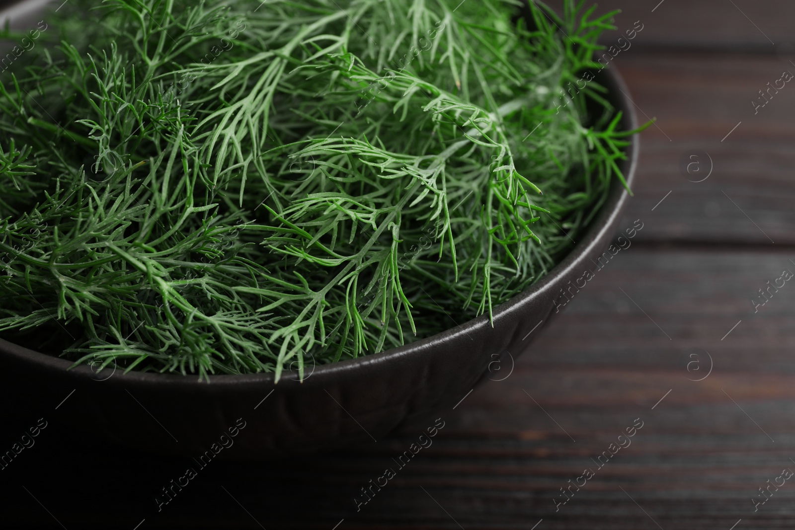 Photo of Bowl of fresh dill on wooden table, closeup. Space for text