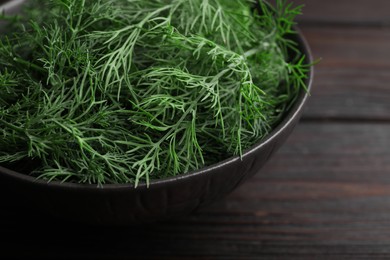 Photo of Bowl of fresh dill on wooden table, closeup. Space for text