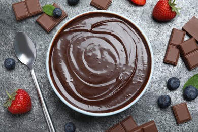 Photo of Delicious chocolate cream with berries and mint on grey table, flat lay