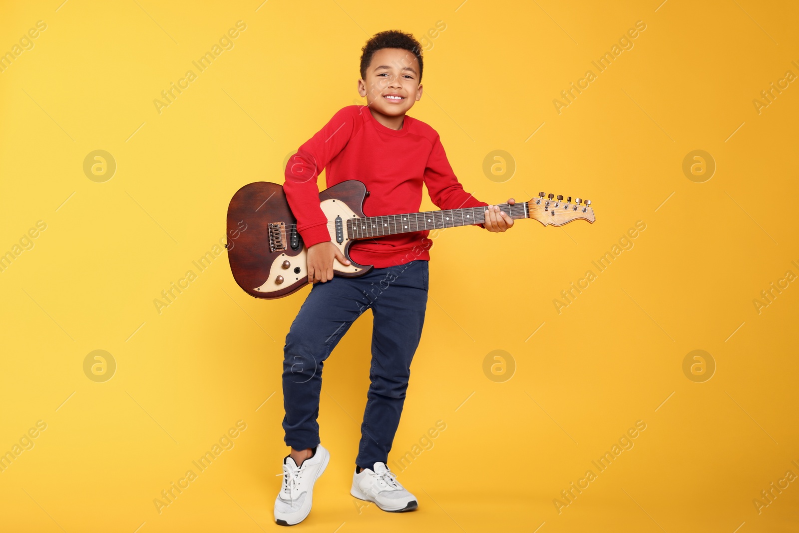 Photo of African-American boy with electric guitar on yellow background