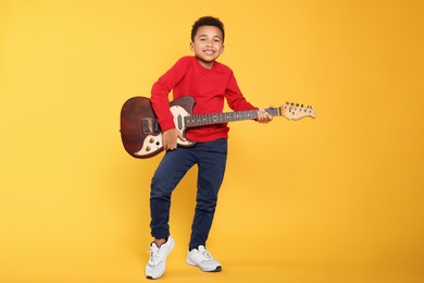 Photo of African-American boy with electric guitar on yellow background
