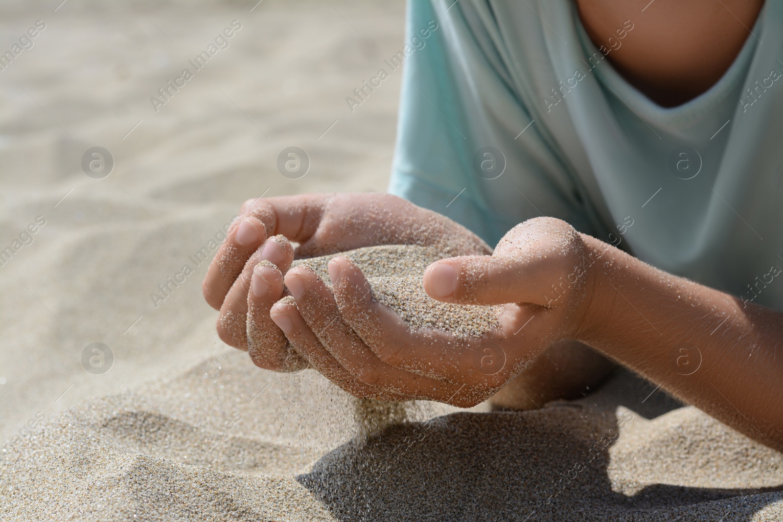 Photo of Child holding sand in hands outdoors, closeup. Fleeting time concept