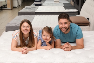 Photo of Happy family lying on new orthopedic mattress in store