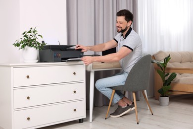 Photo of Man using modern printer at workplace indoors