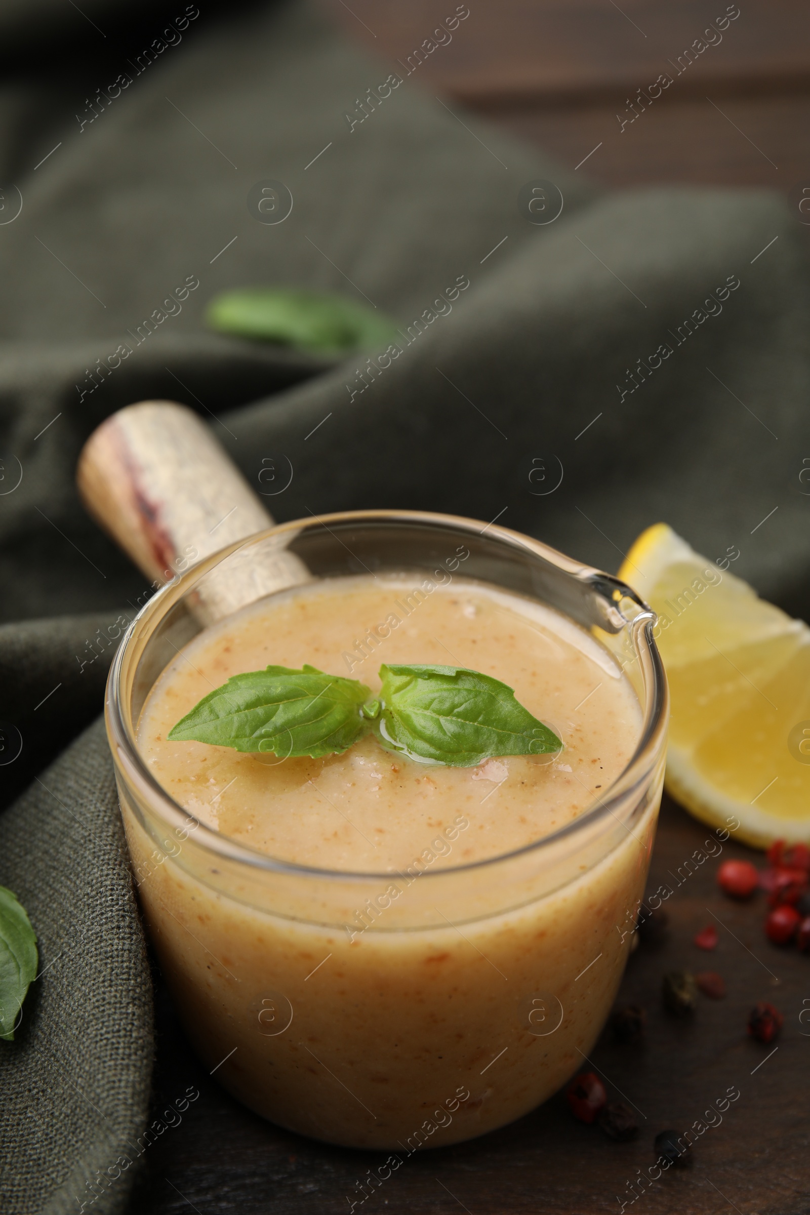 Photo of Delicious turkey gravy, basil, peppercorns and lemon on table, closeup