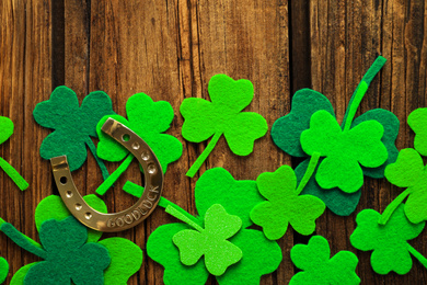 Photo of Flat lay composition with clover leaves and horseshoe on wooden background. St. Patrick's day