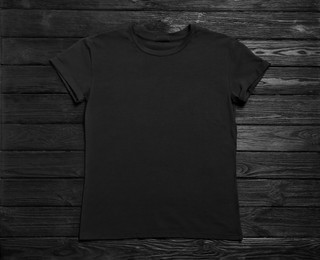 Stylish t-shirt on black wooden background, top view