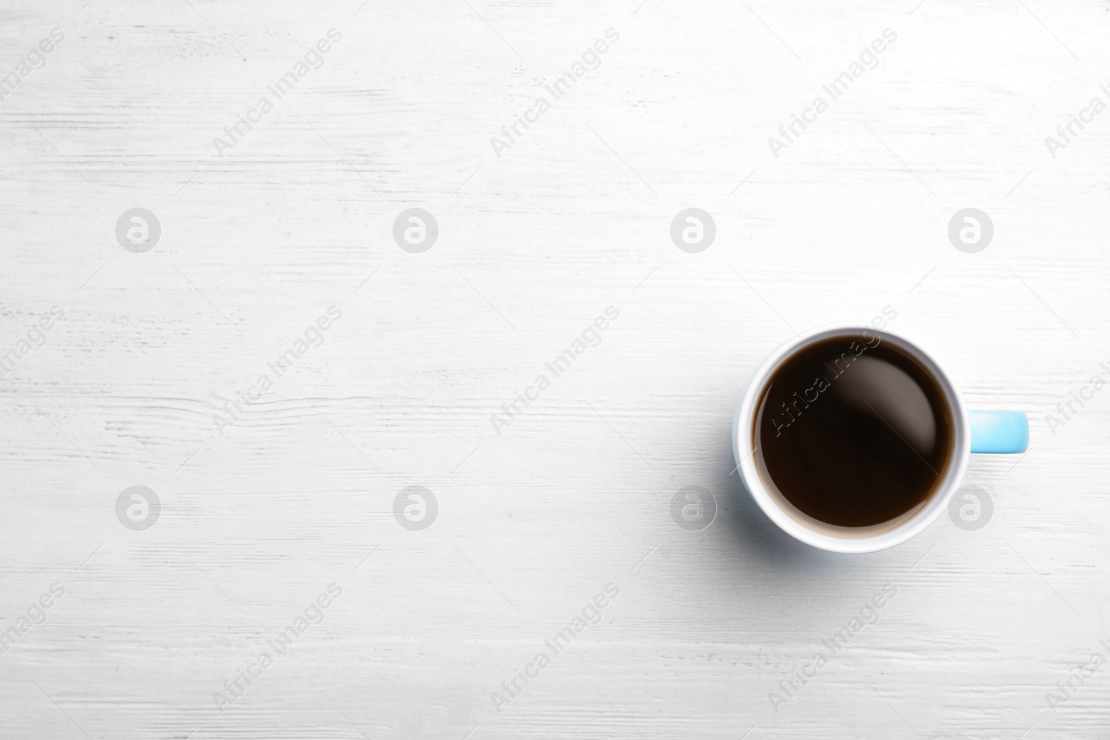 Photo of Ceramic cup with hot aromatic coffee on wooden background, top view