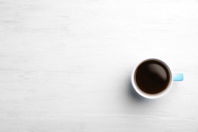 Ceramic cup with hot aromatic coffee on wooden background, top view