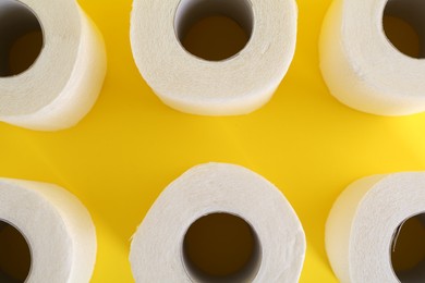 Photo of Many soft toilet paper rolls on yellow background, flat lay