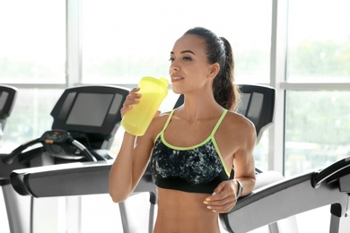 Photo of Portrait of athletic woman with protein shake in gym