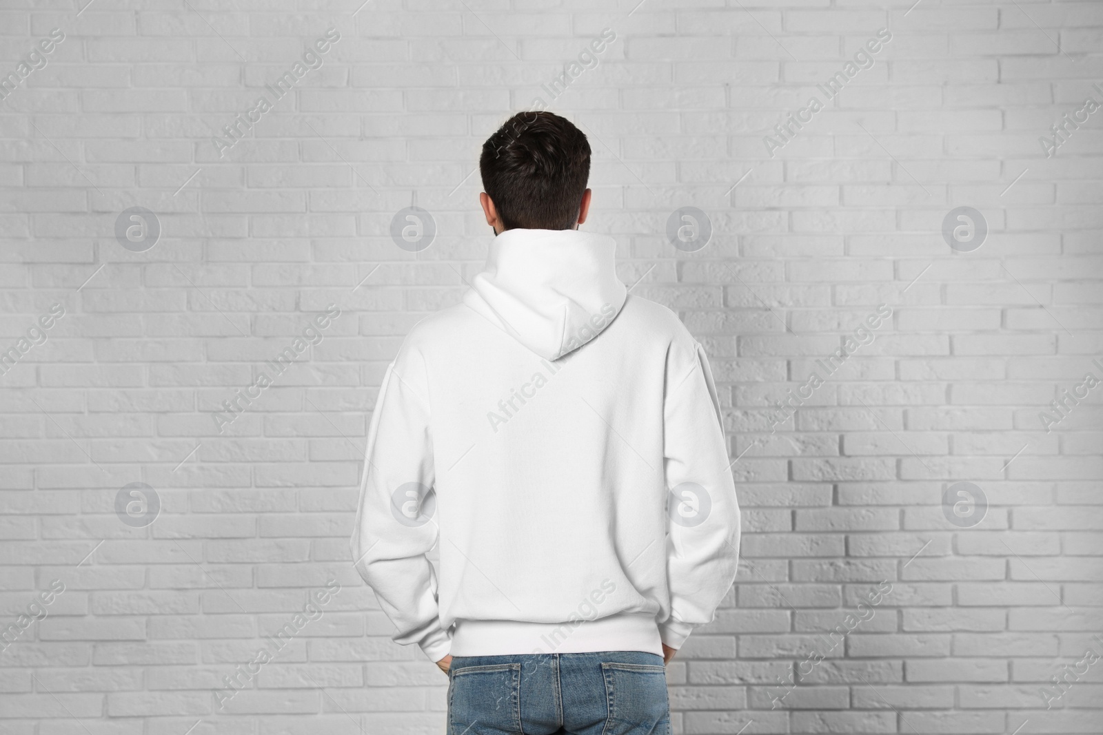 Photo of Young man in sweater at brick wall. Mock up for design