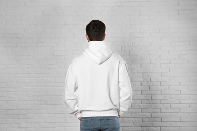 Young man in sweater at brick wall. Mock up for design