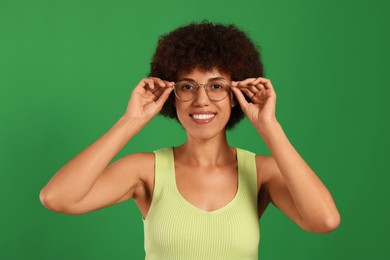 Photo of Portrait of happy young woman in eyeglasses on green background