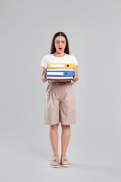 Photo of Shocked woman with folders on light gray background