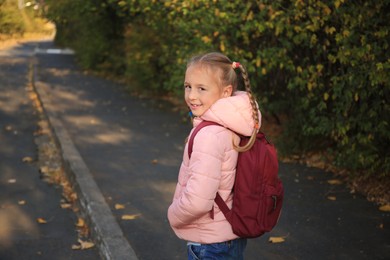 Photo of Cute little girl with backpack on city street