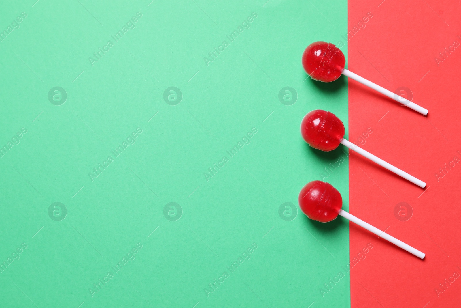 Photo of Three red lollipops on color background, flat lay. Space for text