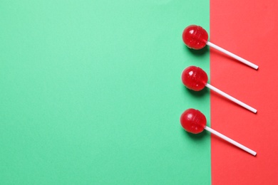Photo of Three red lollipops on color background, flat lay. Space for text