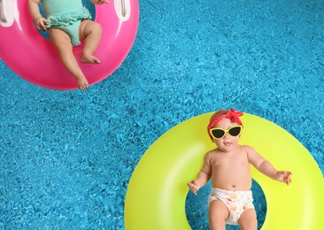 Cute little babies with inflatable rings in swimming pool, top view