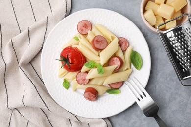 Tasty pasta with smoked sausage, tomato and basil served on light grey table, flat lay