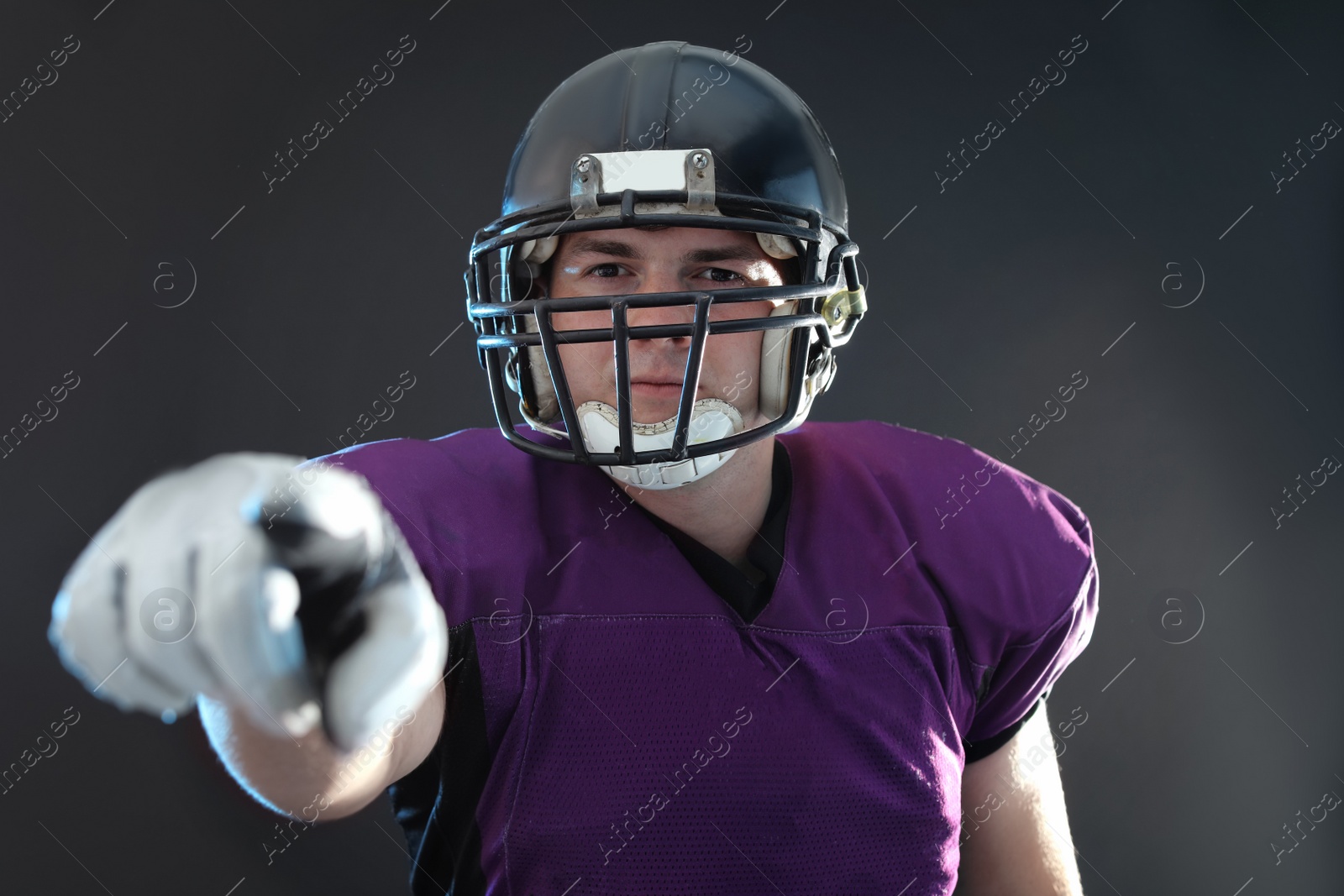 Photo of American football player wearing uniform on dark background