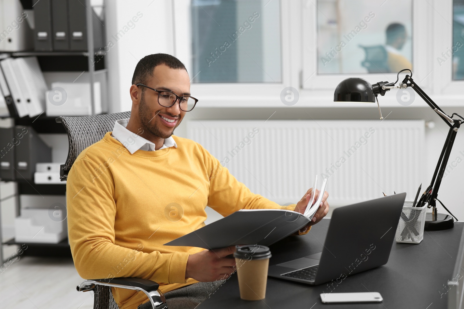 Photo of Young man working with documents at table in office