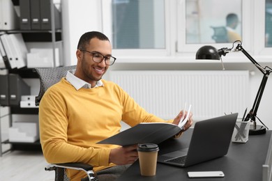 Young man working with documents at table in office