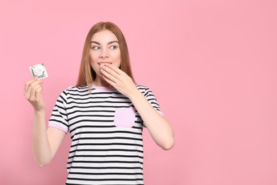 Photo of Woman holding condom on pink background, space for text. Safe sex