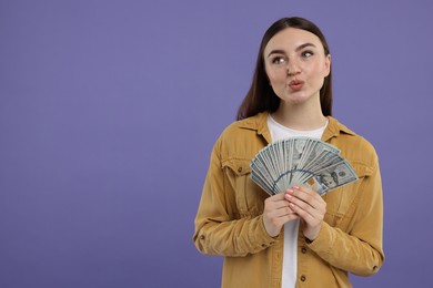 Woman with dollar banknotes on purple background, space for text