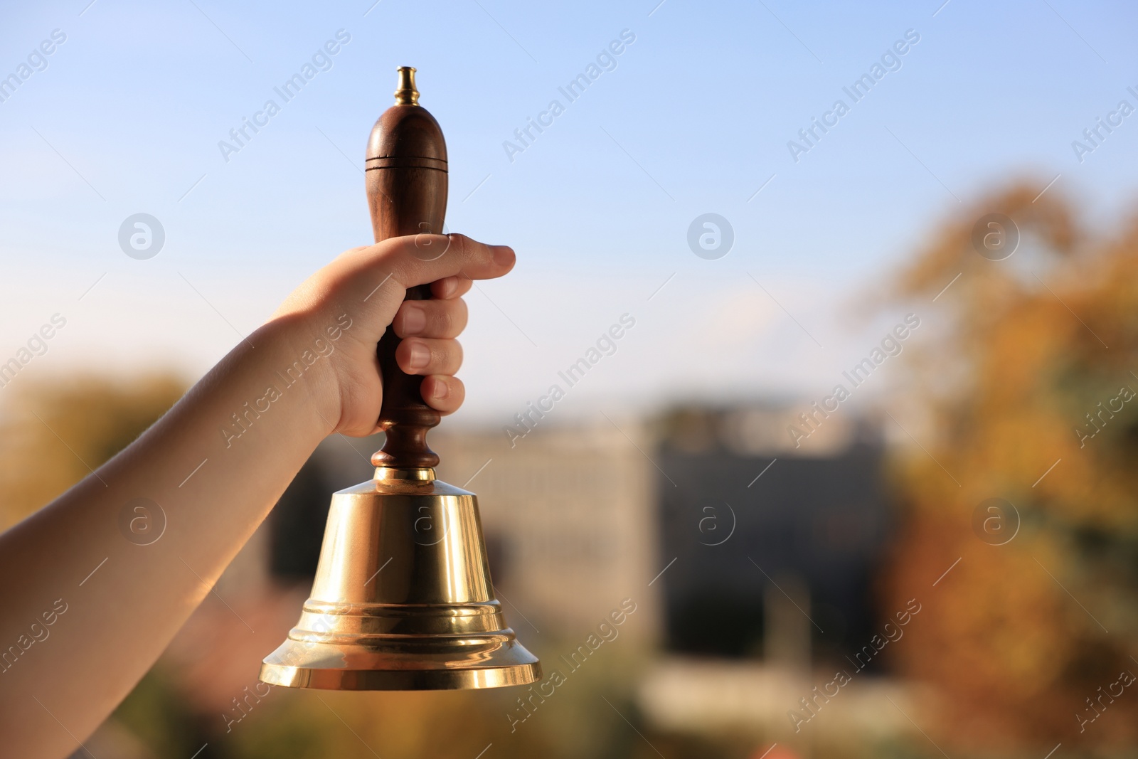 Photo of Pupil with school bell outdoors, closeup. Space for text